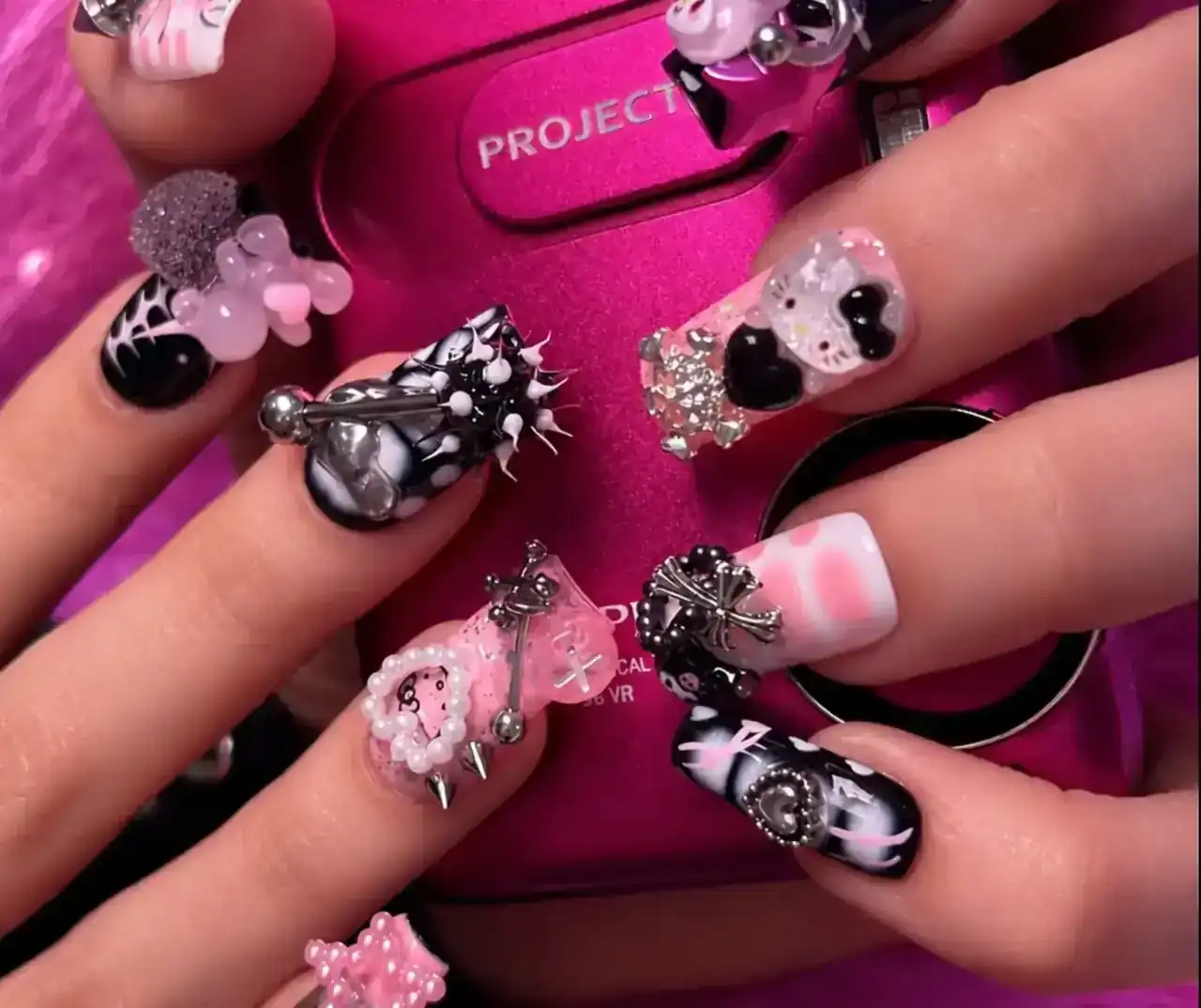 Pink and black Bae Nail designs with silver charms and sculptural embellishments