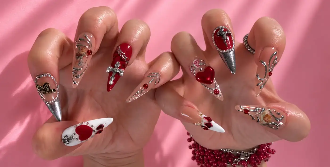 Sculptural silver and red heart nail art photographed against pink satin.