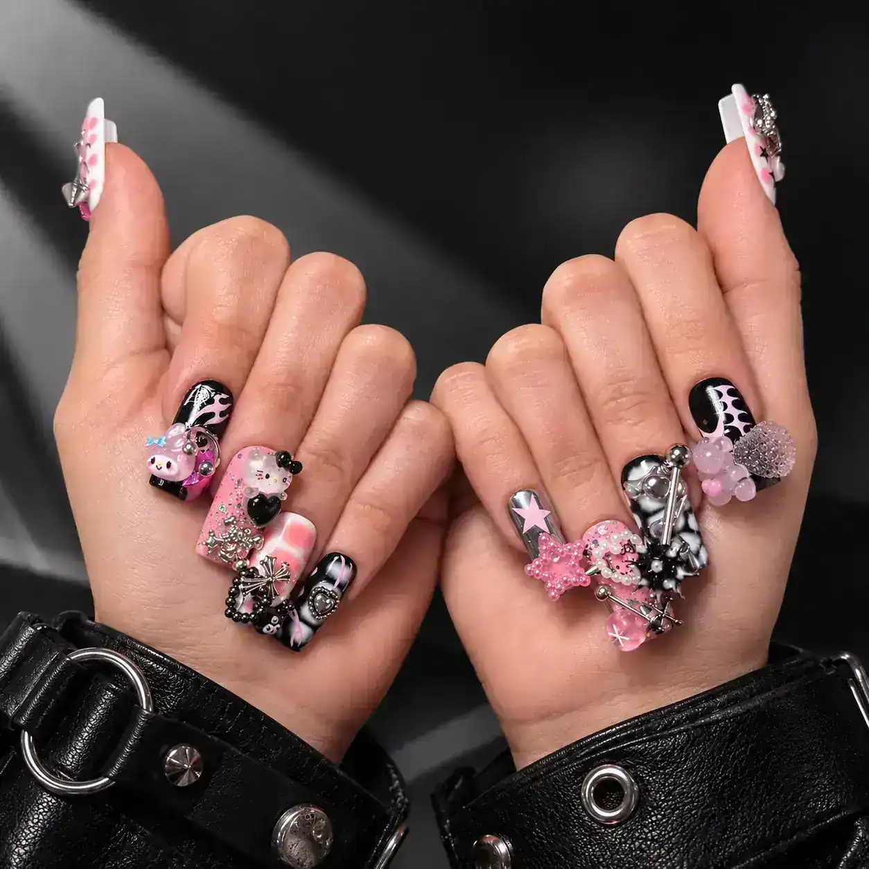 Embellished nails framed by black leather sleeves.